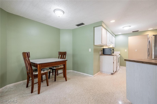 dining room featuring light carpet and a textured ceiling