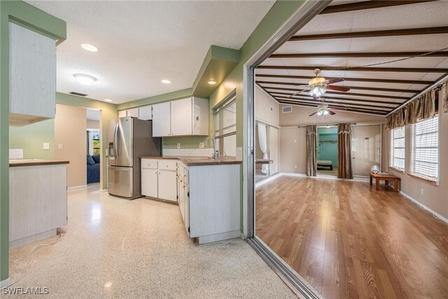 kitchen with vaulted ceiling with beams, stainless steel fridge with ice dispenser, a textured ceiling, white cabinets, and light wood-type flooring