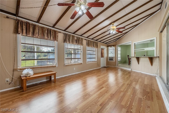 spare room with ceiling fan, a healthy amount of sunlight, wood walls, and light wood-type flooring