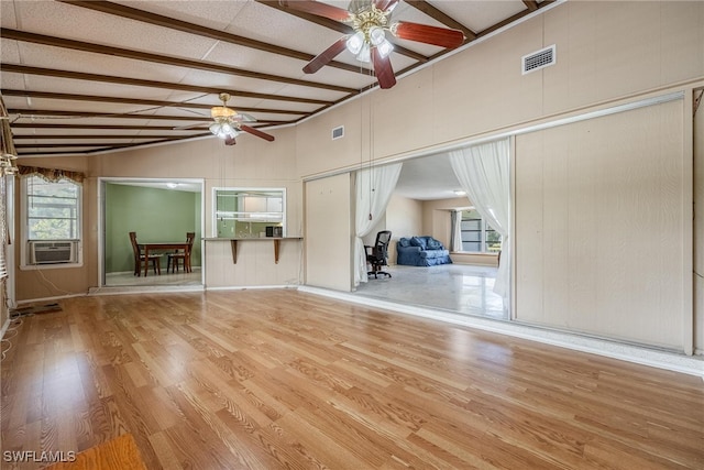 unfurnished living room featuring vaulted ceiling with beams, light hardwood / wood-style floors, ceiling fan, and cooling unit