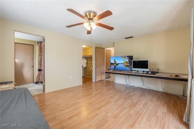 living room with a textured ceiling, light hardwood / wood-style flooring, and ceiling fan