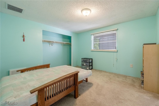 carpeted bedroom featuring a textured ceiling and a closet