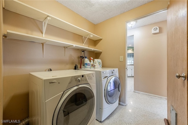 clothes washing area featuring a textured ceiling and washer and clothes dryer