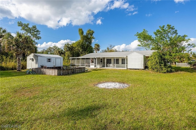 back of house featuring an outbuilding, a yard, and a sunroom