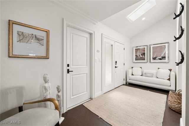 foyer featuring lofted ceiling with skylight, dark wood-type flooring, and crown molding