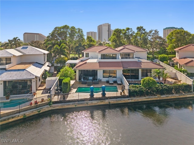 back of house featuring an outdoor living space, a patio area, a fenced in pool, and a water view