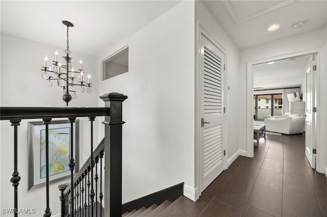 hallway featuring dark tile patterned flooring and a notable chandelier