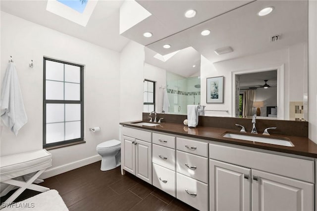5908 Via Lugano, Naples, FL 34108 - bathroom featuring a skylight, a stall shower, baseboards, double vanity, and toilet