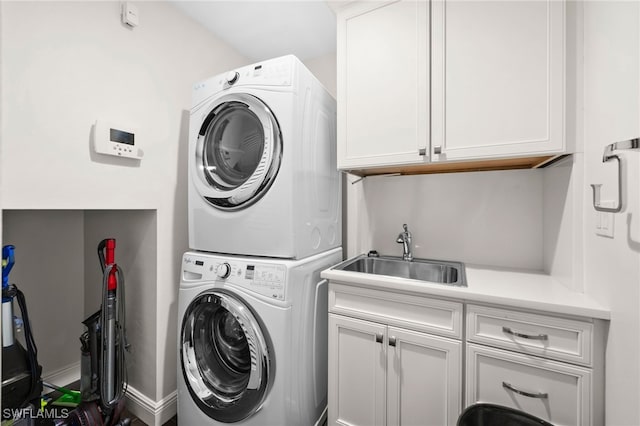 clothes washing area with cabinets, sink, and stacked washer and clothes dryer