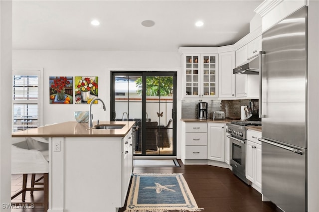 kitchen featuring sink, a kitchen island with sink, dark hardwood / wood-style floors, high quality appliances, and white cabinets