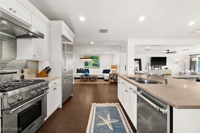 kitchen with high quality appliances, a kitchen island with sink, sink, dark hardwood / wood-style floors, and white cabinetry