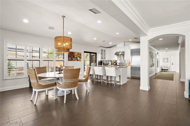 dining space with a chandelier, dark wood-type flooring, vaulted ceiling, and ornamental molding