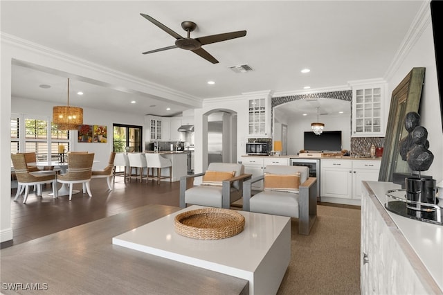 living room with wine cooler, ceiling fan, dark hardwood / wood-style floors, and ornamental molding