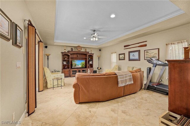 living room featuring a tray ceiling, ceiling fan, and ornamental molding