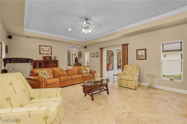 living room featuring a tray ceiling, ceiling fan, and ornamental molding