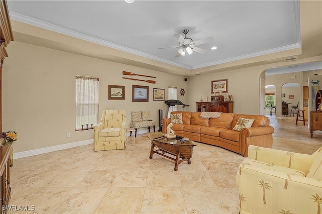 living room featuring a tray ceiling, ceiling fan, and ornamental molding