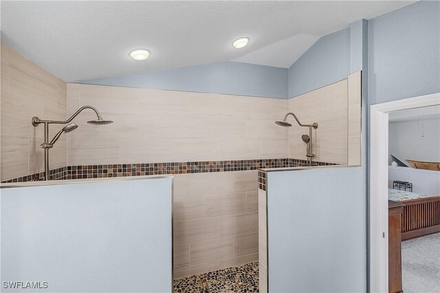 bathroom featuring a tile shower, lofted ceiling, and a textured ceiling