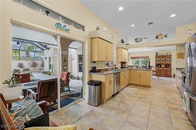 kitchen with kitchen peninsula, appliances with stainless steel finishes, sink, light brown cabinets, and light tile patterned floors