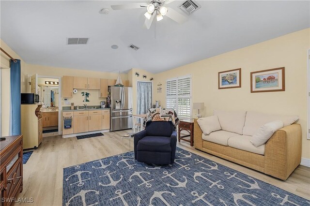 living room with ceiling fan, sink, lofted ceiling, and light wood-type flooring