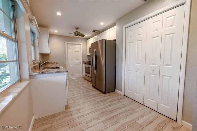 kitchen featuring appliances with stainless steel finishes, ceiling fan, sink, light hardwood / wood-style floors, and white cabinetry