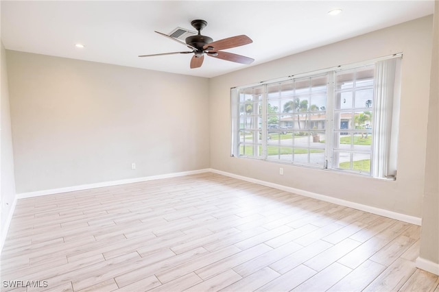 empty room with a wealth of natural light, light hardwood / wood-style flooring, and ceiling fan