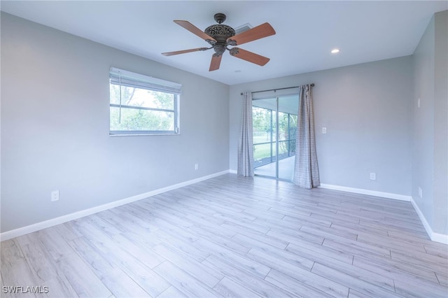 spare room featuring plenty of natural light, ceiling fan, and light wood-type flooring