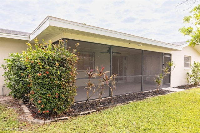 view of home's exterior with a yard, ceiling fan, and a sunroom