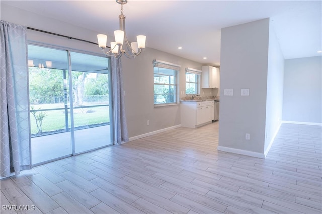 empty room featuring light hardwood / wood-style floors, a notable chandelier, and sink