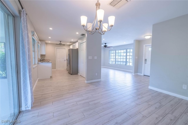 interior space with ceiling fan with notable chandelier and light hardwood / wood-style flooring