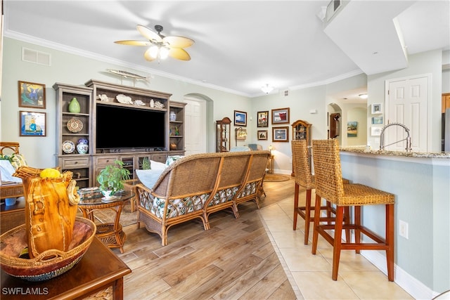 living room featuring crown molding, ceiling fan, sink, and light hardwood / wood-style flooring