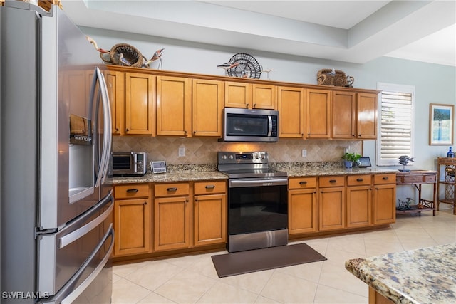 kitchen featuring light stone counters, light tile patterned floors, tasteful backsplash, and appliances with stainless steel finishes