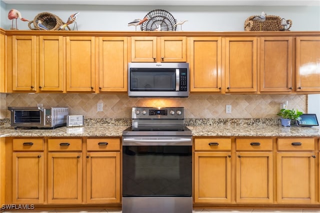 kitchen with light stone counters, decorative backsplash, and stainless steel appliances