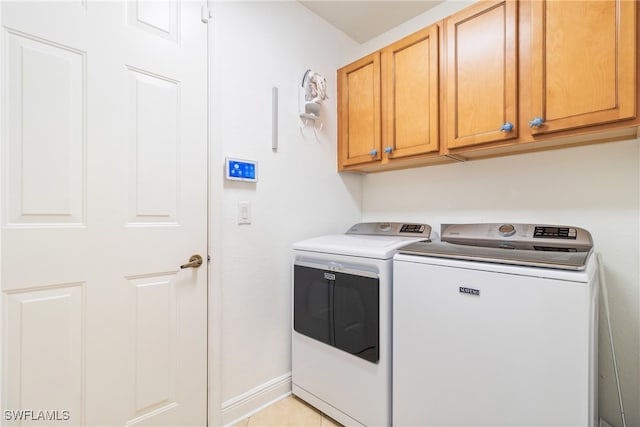 clothes washing area with cabinets, light tile patterned flooring, and washer and dryer