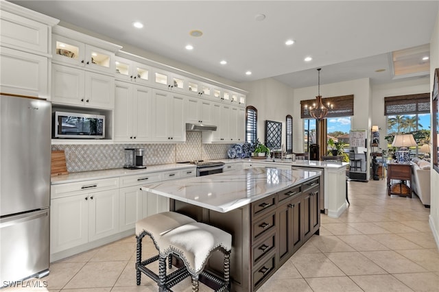 12656 Grandezza Cir, Estero, FL 33928 - kitchen with stainless steel appliances, light tile patterned floors, under cabinet range hood, a peninsula, and white cabinets
