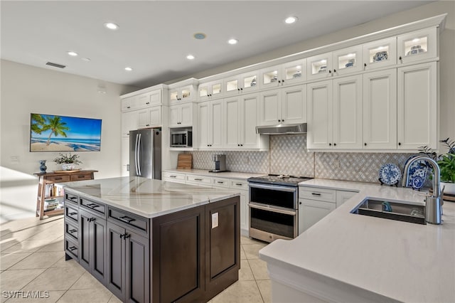 12656 Grandezza Cir, Estero, FL 33928 - kitchen with stainless steel appliances, under cabinet range hood, white cabinets, light tile patterned floors, and recessed lighting