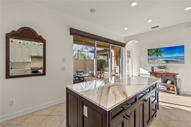 12656 Grandezza Cir, Estero, FL 33928 - kitchen with arched walkways, light tile patterned floors, light stone counters, backsplash, and recessed lighting