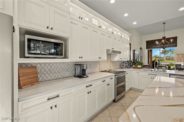 kitchen featuring hanging light fixtures, light tile patterned floors, light stone counters, white cabinets, and appliances with stainless steel finishes