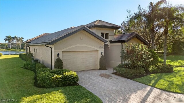 12656 Grandezza Cir, Estero, FL 33928 - mediterranean / spanish house featuring an attached garage, a water view, stucco siding, decorative driveway, and a front yard