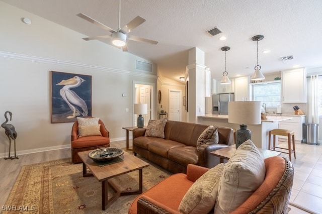 living room featuring a textured ceiling, light hardwood / wood-style floors, ceiling fan, and lofted ceiling