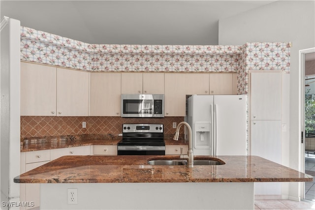 kitchen with backsplash, dark stone counters, sink, appliances with stainless steel finishes, and light tile patterned flooring