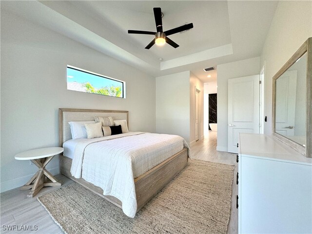 bedroom featuring a tray ceiling, light hardwood / wood-style flooring, and ceiling fan