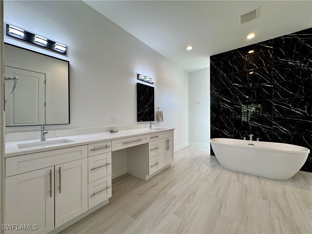 bathroom with a bathing tub, vanity, and tile walls