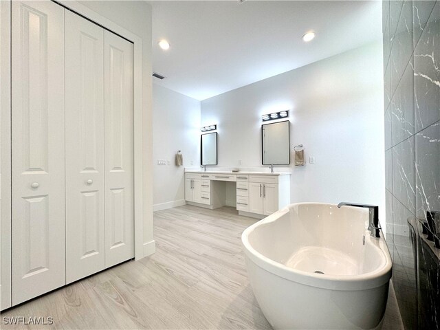 bathroom with hardwood / wood-style floors, vanity, and a tub