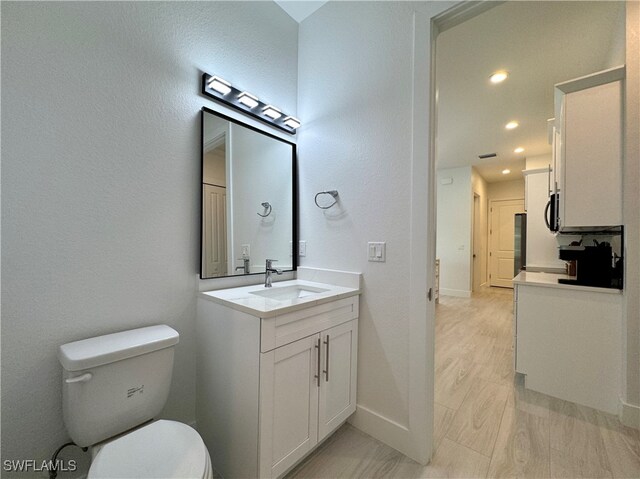 bathroom with vanity, hardwood / wood-style flooring, and toilet