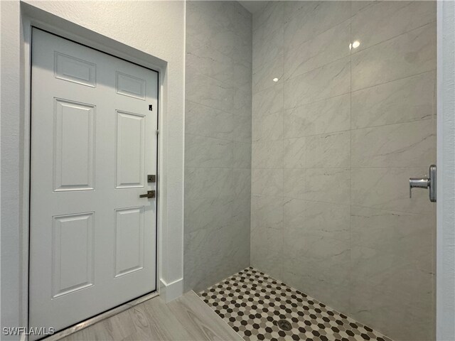 bathroom with a tile shower and hardwood / wood-style flooring