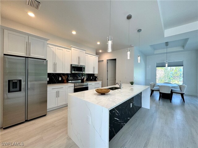 kitchen with white cabinets, hanging light fixtures, and appliances with stainless steel finishes