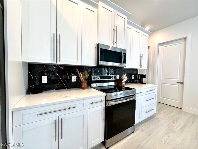 kitchen featuring decorative backsplash, light stone counters, white cabinetry, and stainless steel appliances