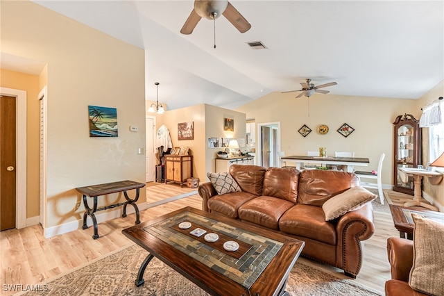 living room with ceiling fan with notable chandelier, light wood-type flooring, and vaulted ceiling