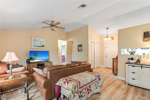 living room with ceiling fan with notable chandelier, light hardwood / wood-style flooring, and lofted ceiling