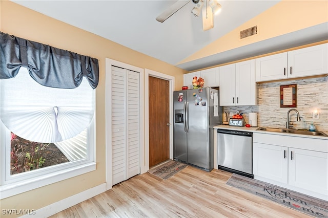 kitchen with appliances with stainless steel finishes, backsplash, sink, white cabinetry, and lofted ceiling